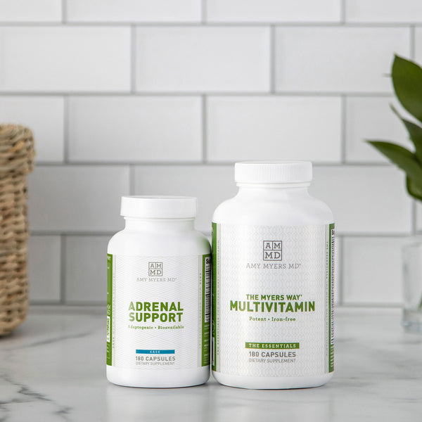 Adrenal Support capsule bottle next to a Multivitamin capsule bottle sitting on a white granite countertop with white tile background. 
